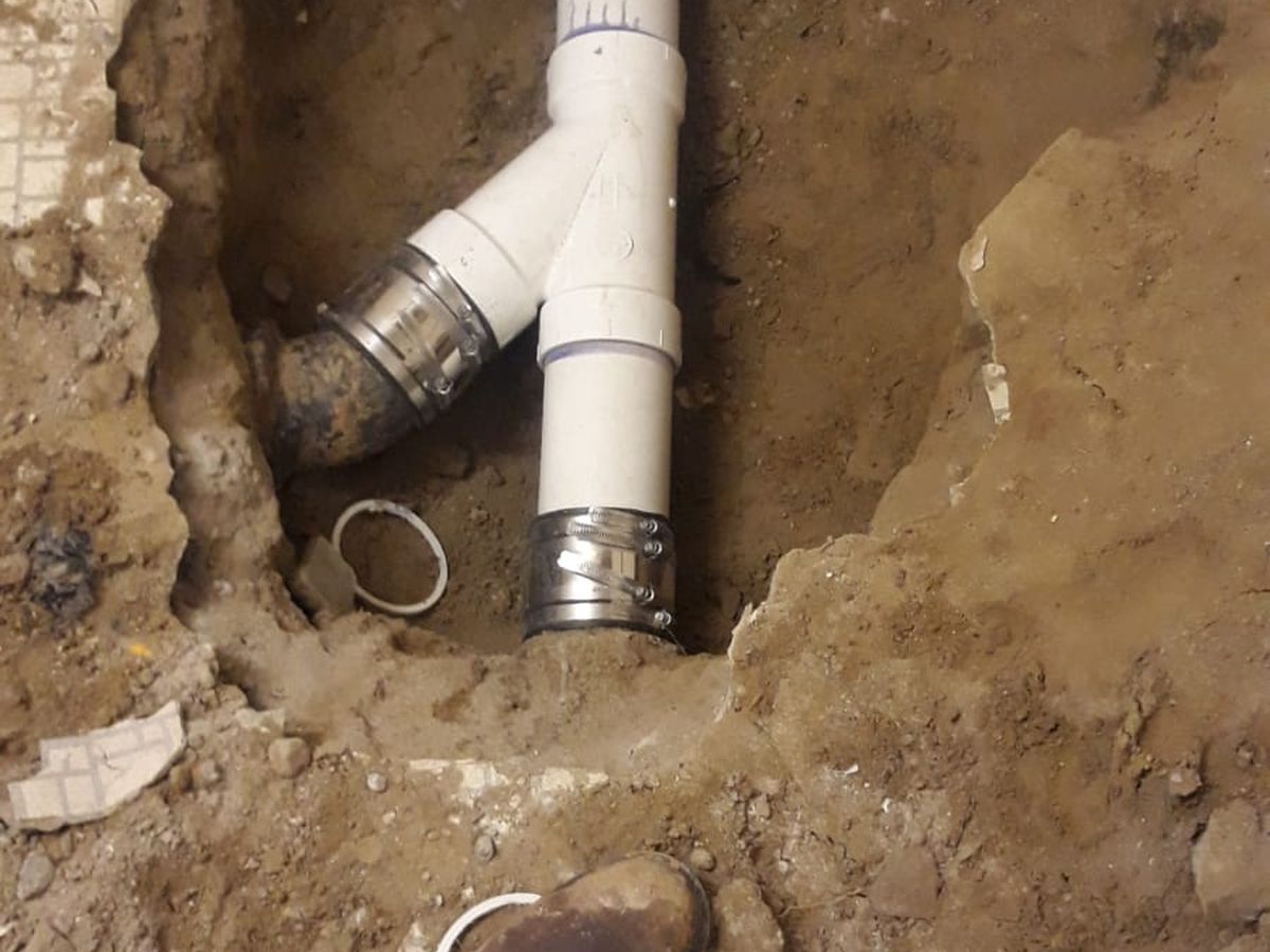 New PVC wye and cleanout riser cut into a sewer line in a small excavation
