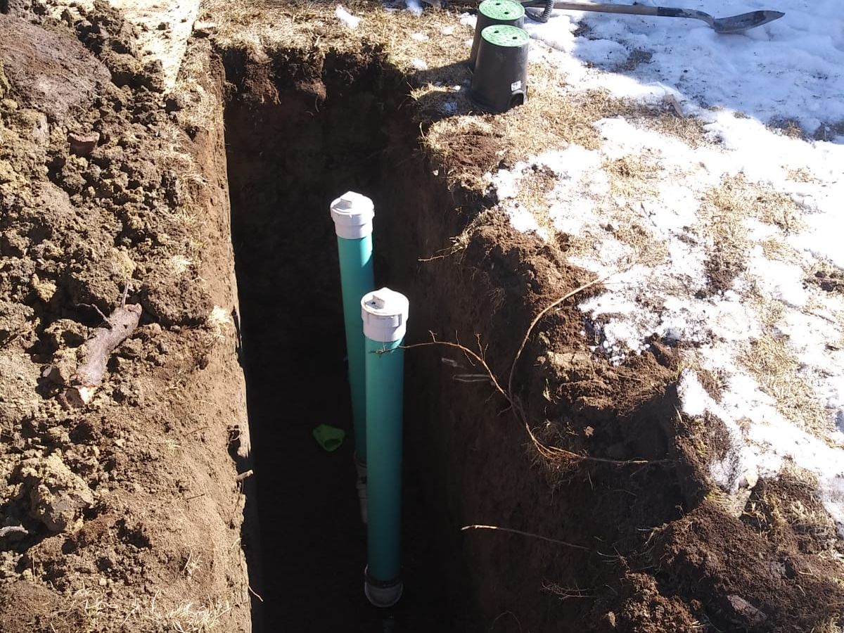 Two cleanout risers side by side in a trench for a two-way cleanout