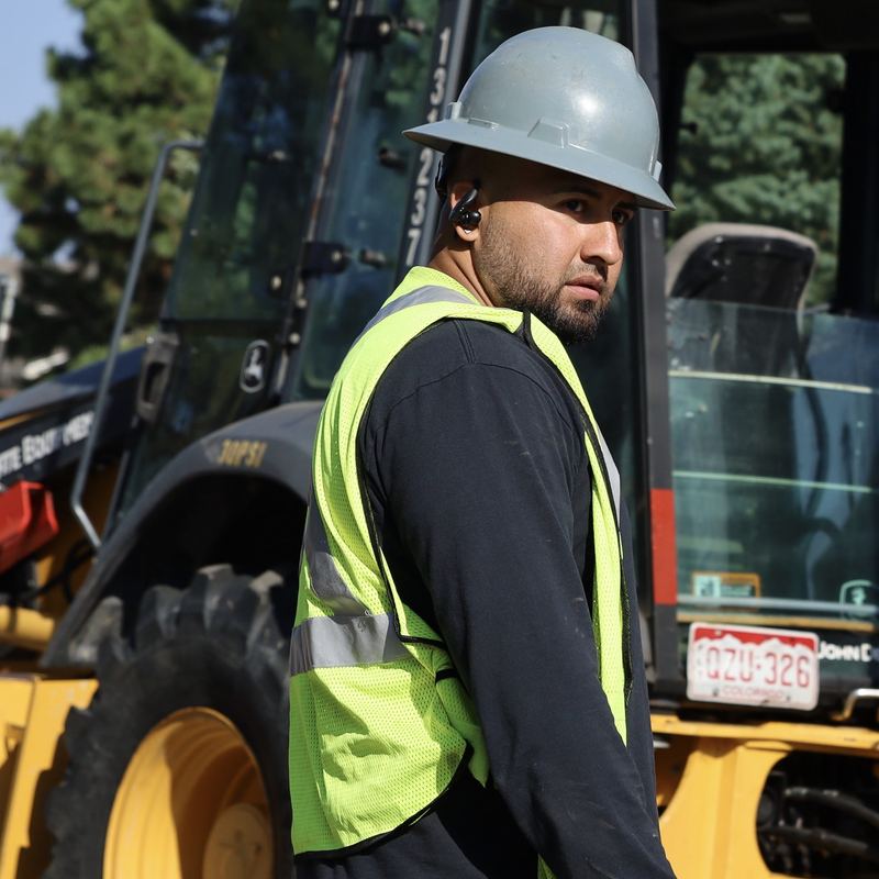 Crew members beside a backhoe on a street job