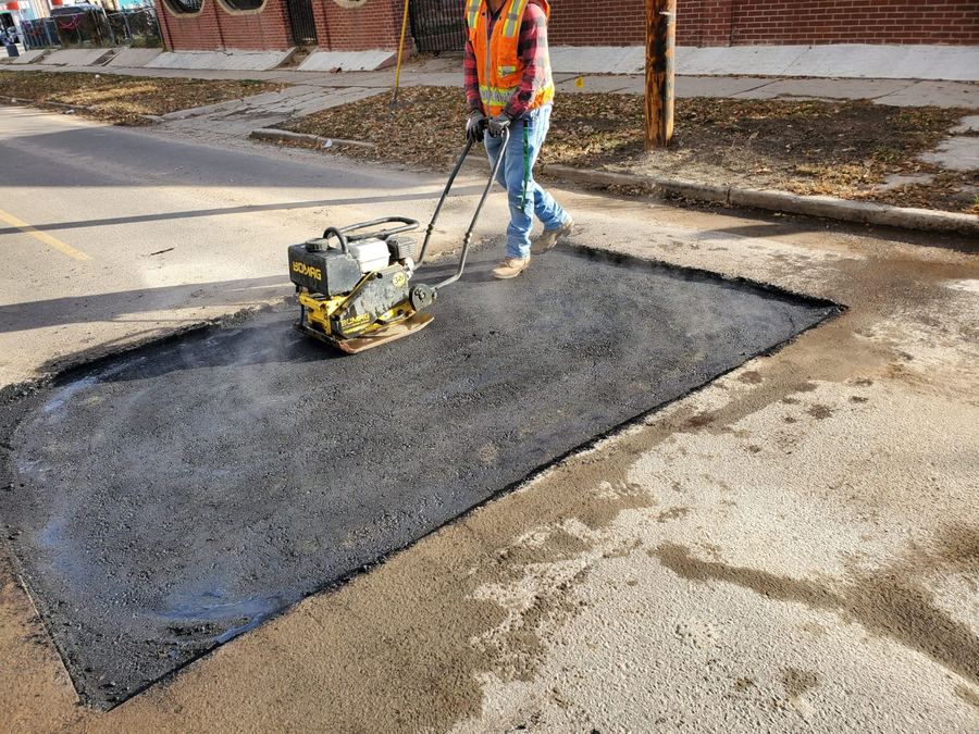 Crew member running a plate compactor over backfilled trench