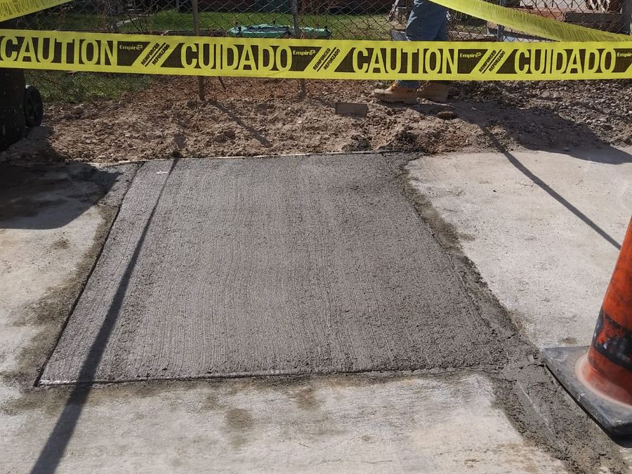 Freshly poured concrete sidewalk patch after a sewer excavation