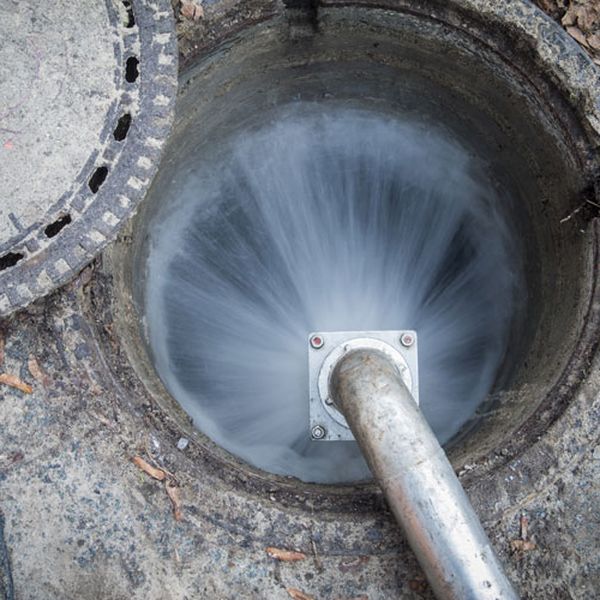 Hydro jetting hose spraying high-pressure water inside a sewer manhole