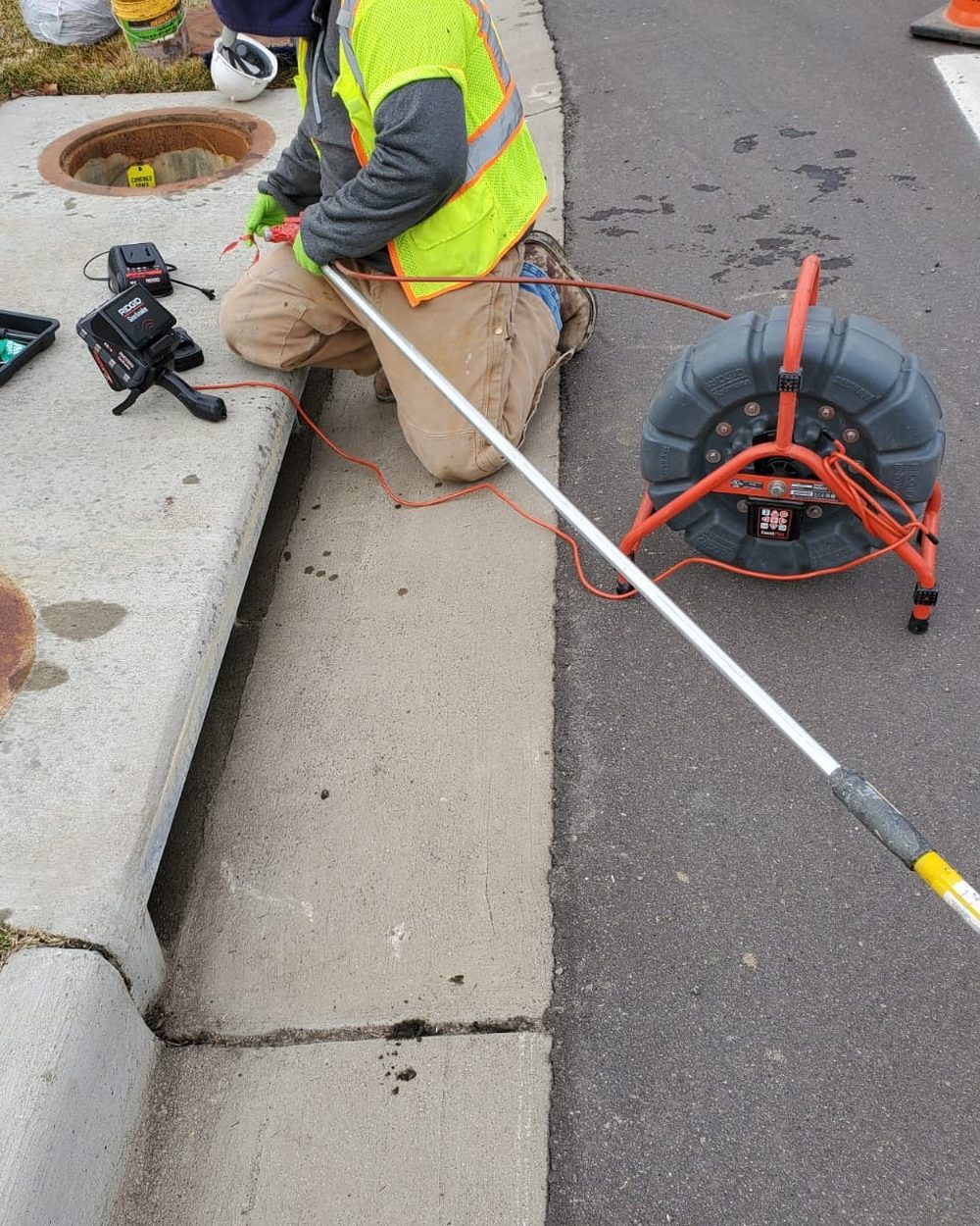 Sewer Experts technician running a locating camera into a sewer line from a curbside cleanout in Denver