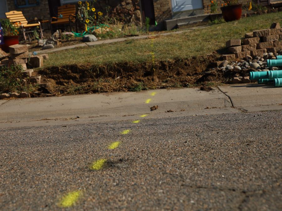 Yellow locate marks painted along a Denver street showing the path of a buried line