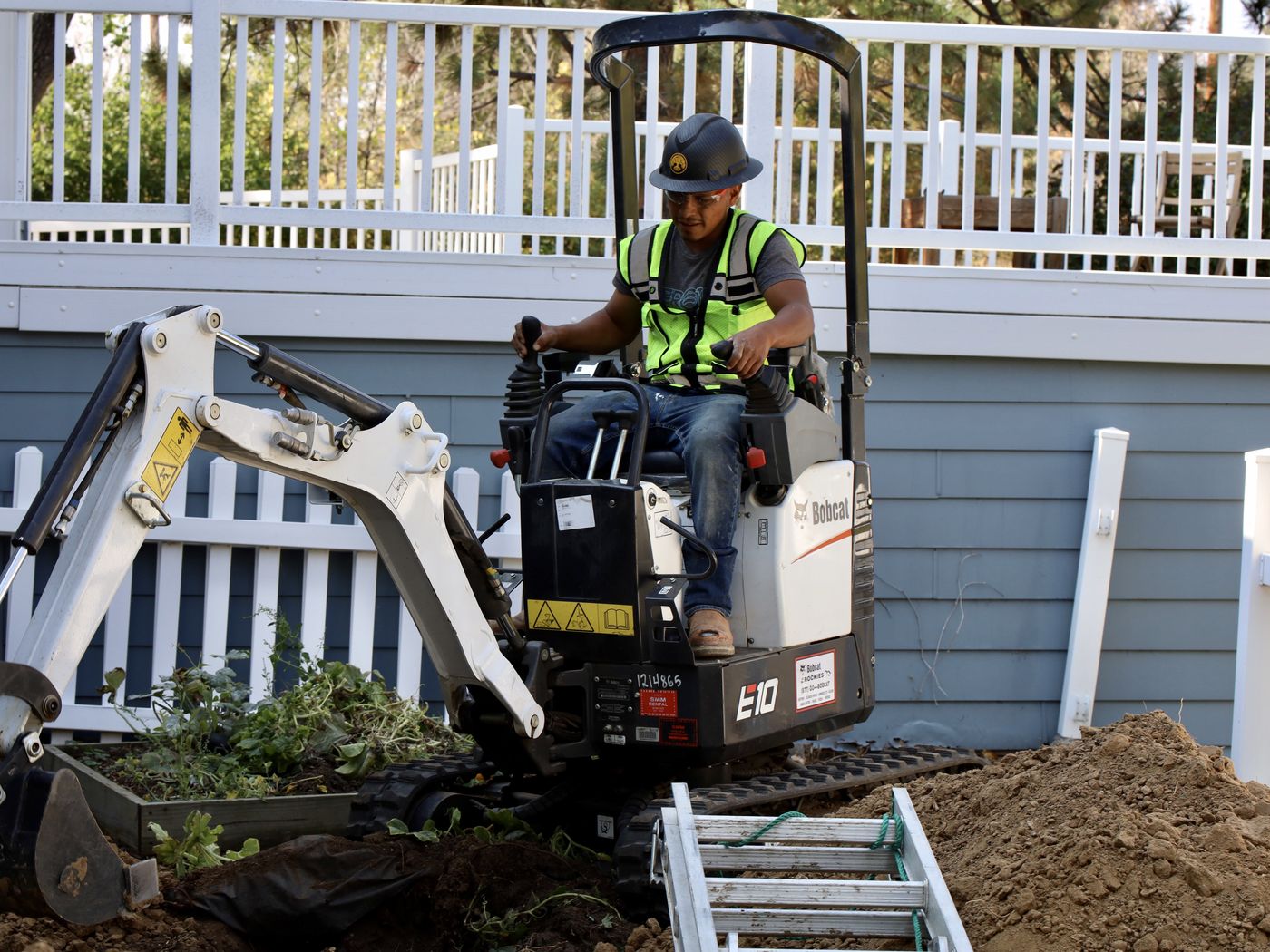 Sewer Experts crew running a mini excavator beside a Denver home