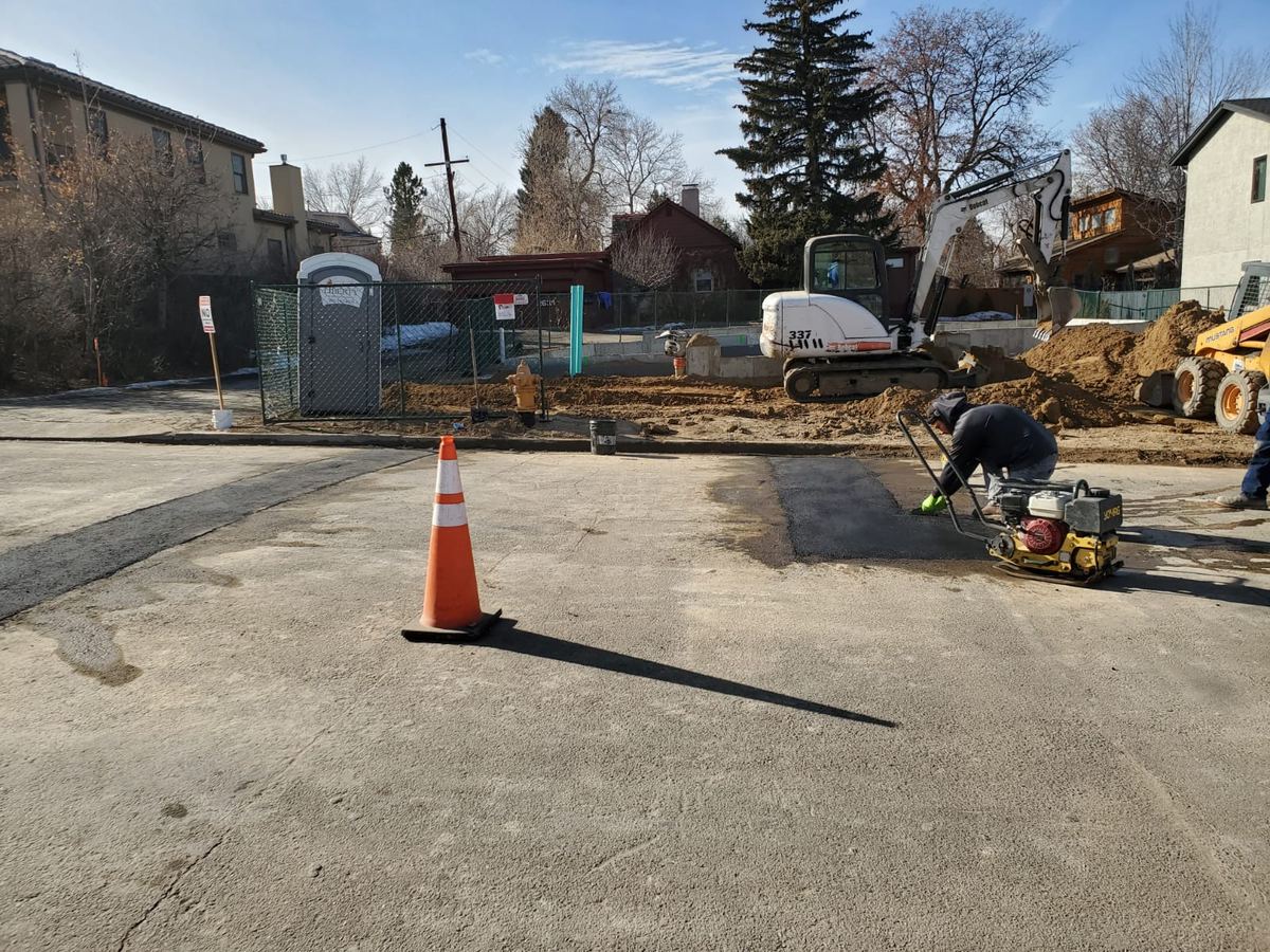 Commercial parking lot with fresh asphalt patch after storm drain work